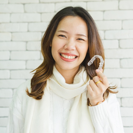 Smiling woman holding an Invisalign tray